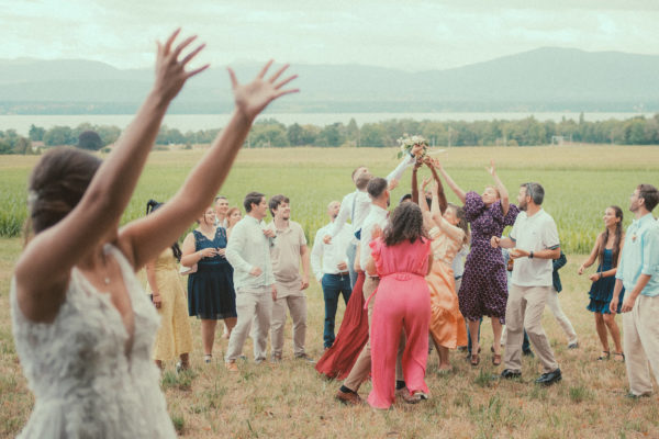 Lancer de bouquet animé dans un champ en Suisse, ambiance joyeuse et rires partagés entre invités