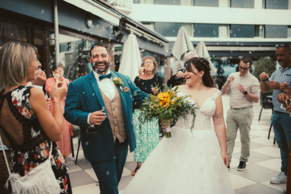 Sortie des mariés sous les bulles, regards heureux et ambiance festive au cocktail de mariage