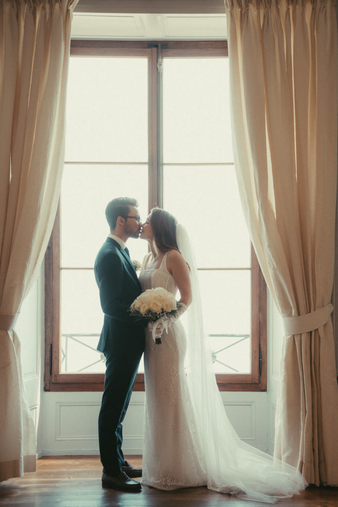 Couple de mariés dans devant la fenêtre du château de Nyon