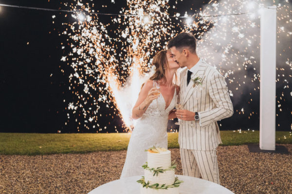 Couple découpant le gâteau de mariage avec des étincelles